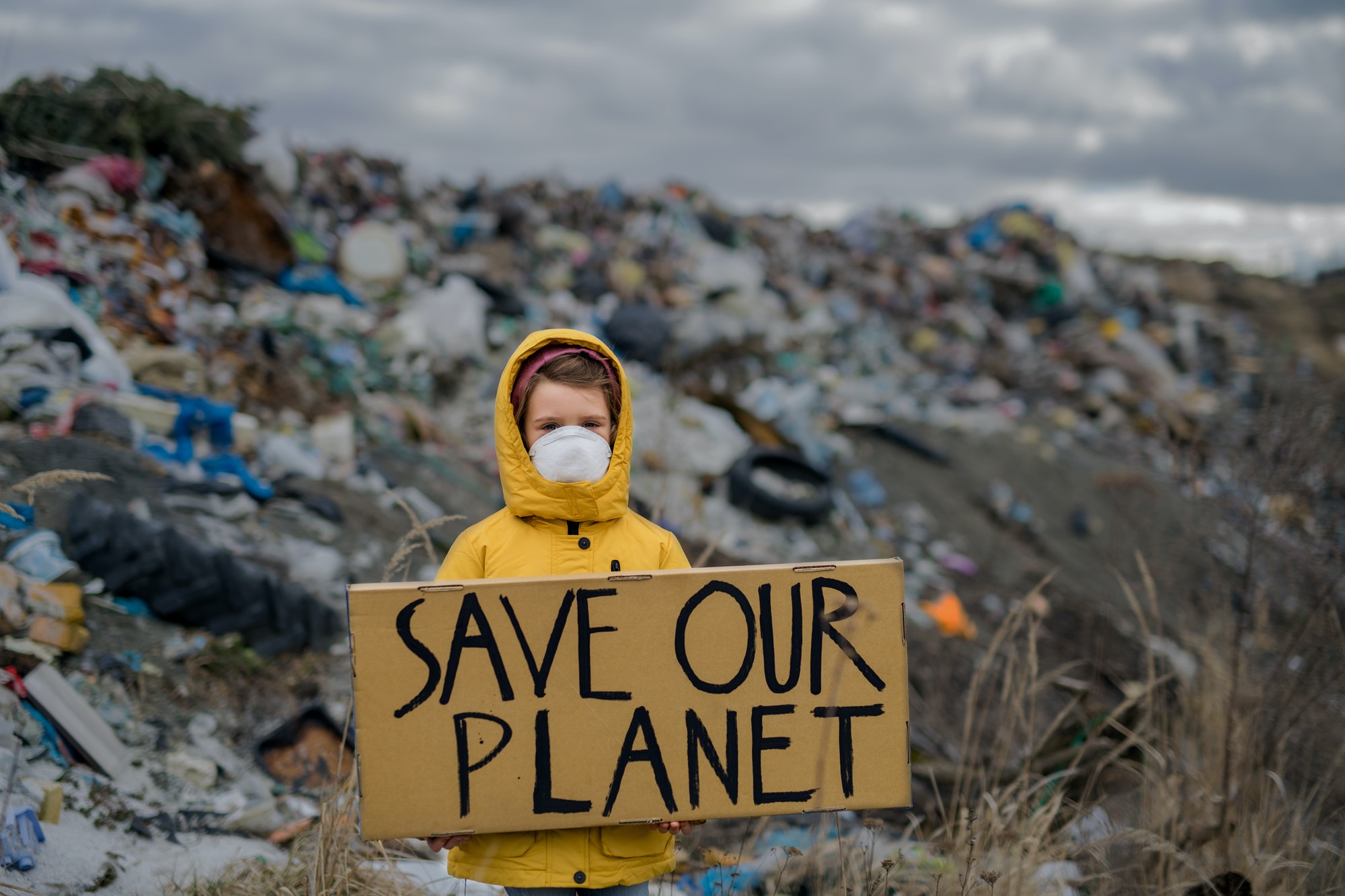 Small child holding placard poster on landfill, environmental pollution concept